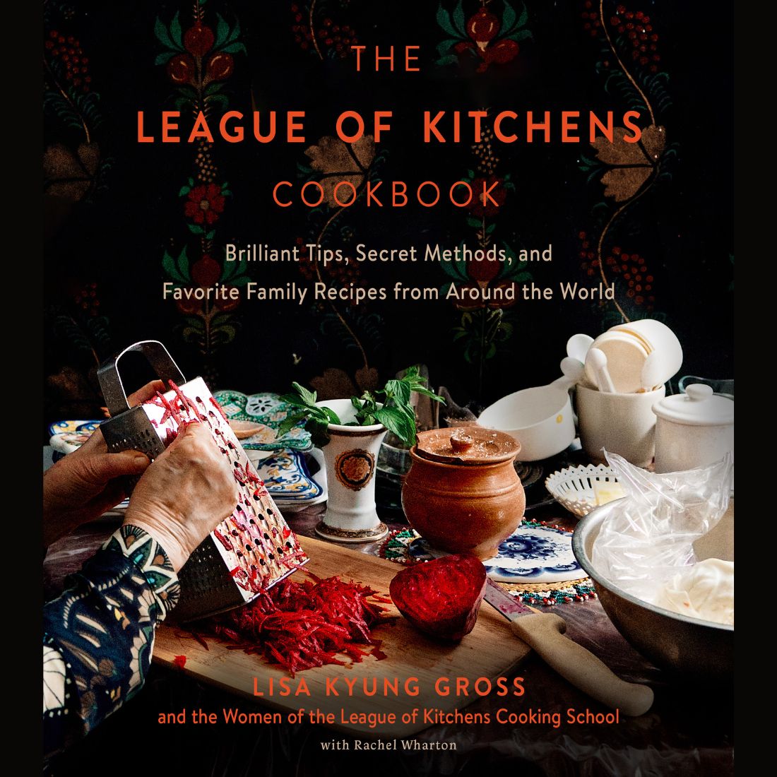 Cover of The League of Kitchens Cookbook by Lisa Kyung Gross, featuring hands grating red vegetables over a wooden board, surrounded by vibrant dishes and kitchenware